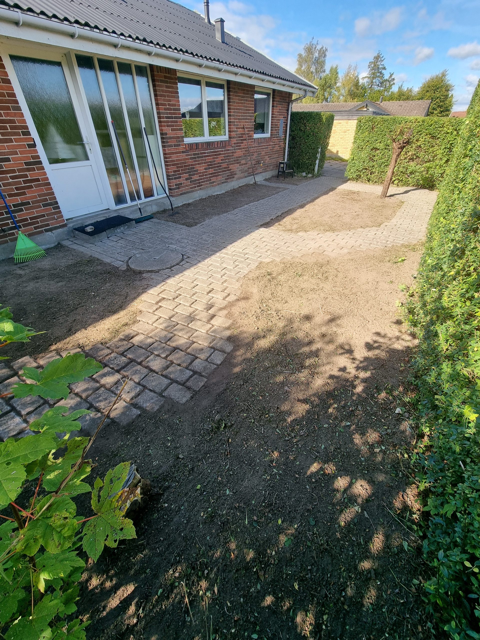 En ren og pæn flisesti efter professionel ukrudtsbekæmpelse og havepleje, hvor alle bede er luget og jorden er klargjort.