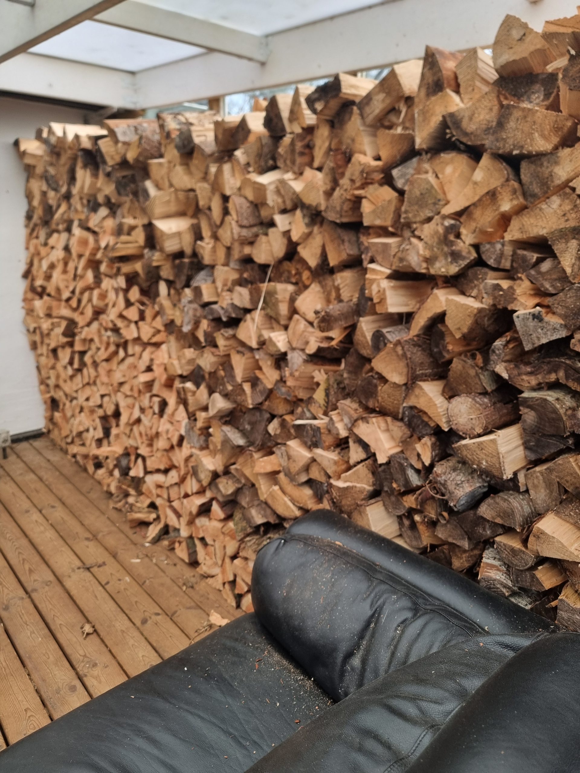 Store, runde træstammer og kævler stablet efter træfældning, klar til at blive kløvet til brænde.